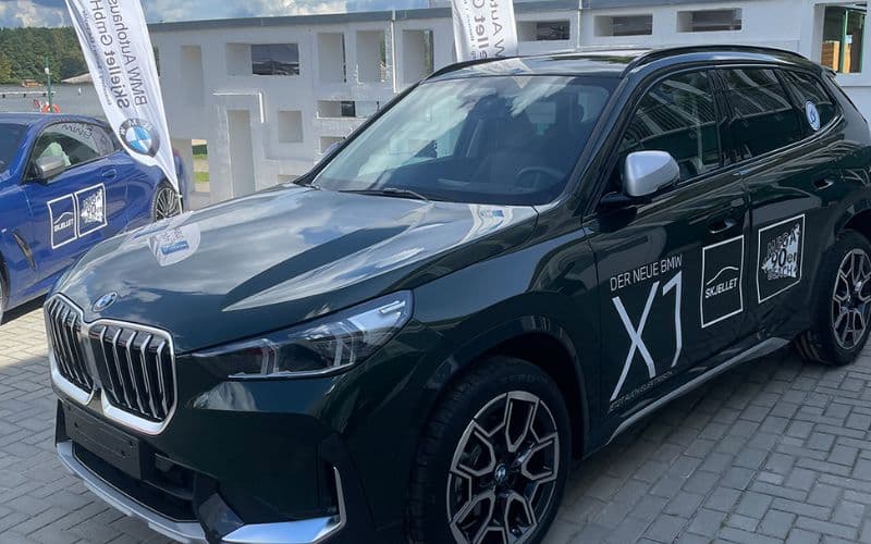 BMW X1 mit Aktionsbeklebung "Der neue BMW X1" und Skjellet-Branding vor dem Strandbad Grünau
